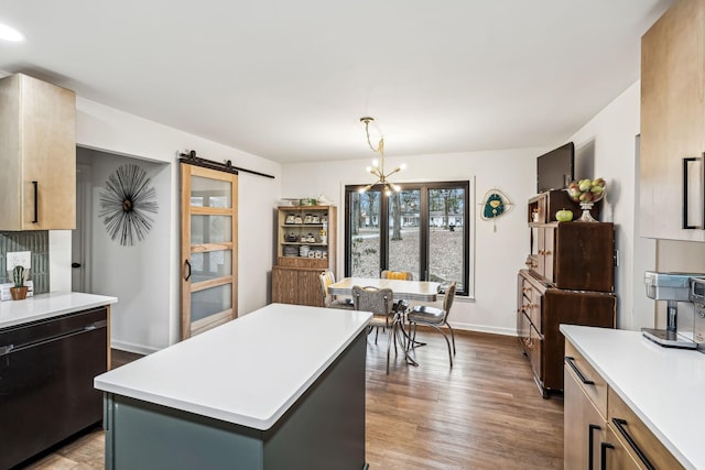 kitchen featuring dishwasher, a kitchen island, wood-type flooring, hanging light fixtures, and a barn door