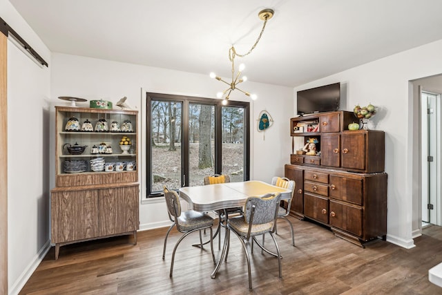 dining room featuring dark wood-type flooring, an inviting chandelier, and a barn door