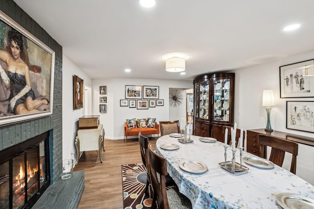 dining room featuring a brick fireplace and light hardwood / wood-style flooring