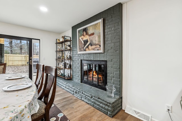 dining space with a brick fireplace and wood-type flooring