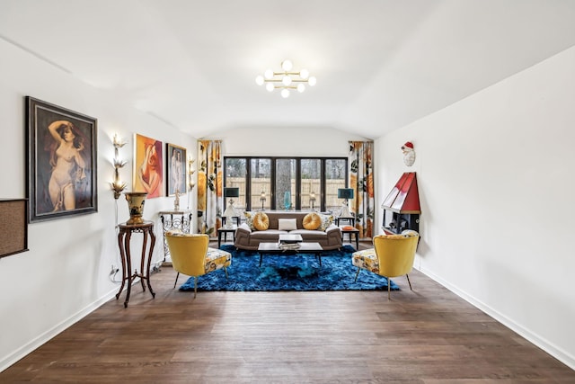 living room with hardwood / wood-style flooring, a notable chandelier, and vaulted ceiling