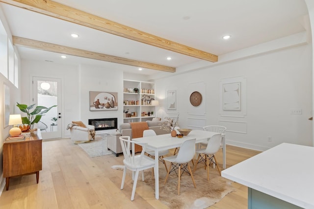 dining space with light hardwood / wood-style floors, built in shelves, and beamed ceiling