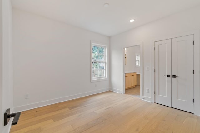 unfurnished bedroom with light hardwood / wood-style flooring and connected bathroom