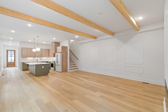 unfurnished living room with sink, light wood-type flooring, and beam ceiling