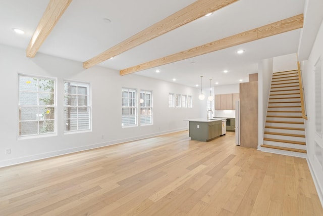 unfurnished living room featuring sink, light hardwood / wood-style flooring, and beam ceiling