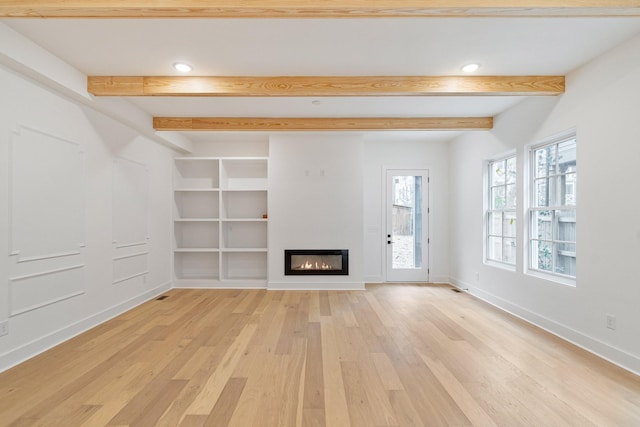 unfurnished living room featuring light wood-type flooring, built in shelves, and beam ceiling