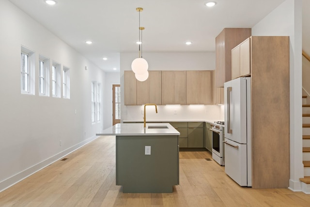 kitchen with sink, decorative light fixtures, white range with gas cooktop, a center island with sink, and high end refrigerator