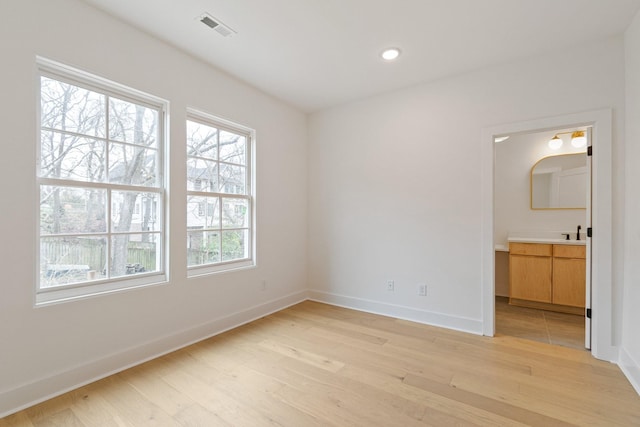 unfurnished bedroom featuring sink, ensuite bathroom, and light hardwood / wood-style flooring