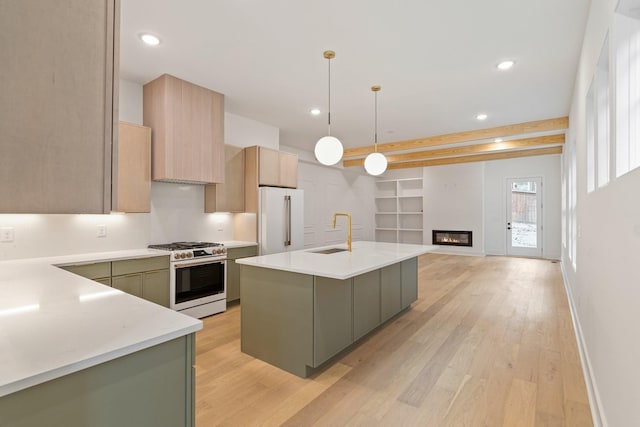 kitchen featuring pendant lighting, a kitchen island with sink, green cabinetry, gas range oven, and high end fridge