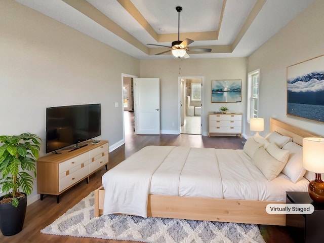 bedroom with ceiling fan, dark hardwood / wood-style flooring, and a raised ceiling