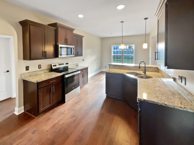 kitchen with sink, pendant lighting, light stone countertops, and appliances with stainless steel finishes