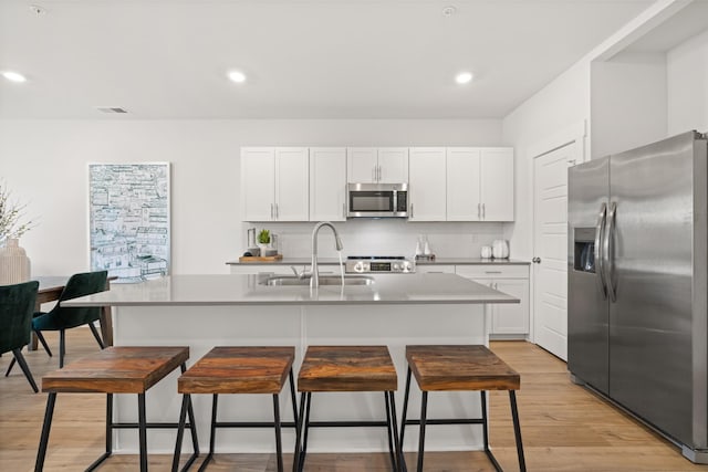 kitchen with a kitchen island with sink, white cabinetry, and stainless steel appliances