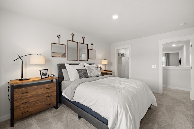 bedroom with light colored carpet, a closet, and a walk in closet