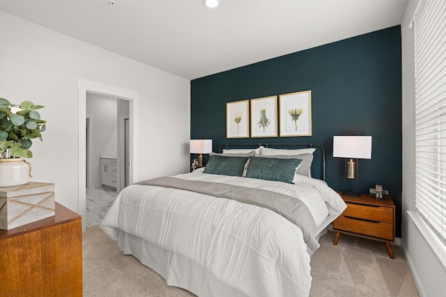 bedroom featuring light colored carpet and ensuite bath