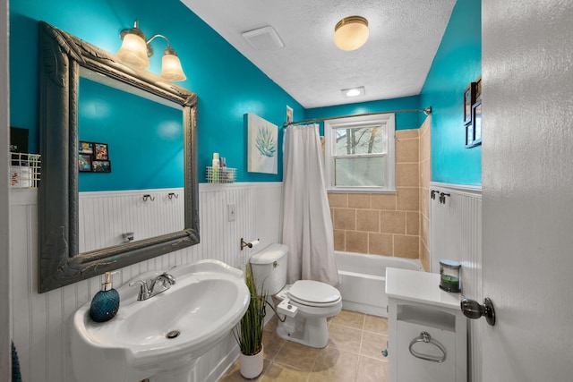 full bathroom featuring a textured ceiling, tile patterned flooring, shower / tub combo, sink, and toilet