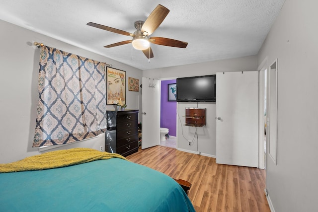 bedroom with ceiling fan, ensuite bathroom, a textured ceiling, and hardwood / wood-style flooring