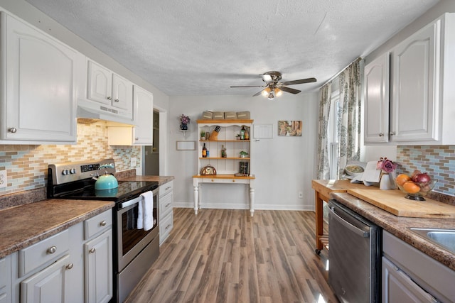 kitchen with backsplash, white cabinets, light hardwood / wood-style flooring, and appliances with stainless steel finishes