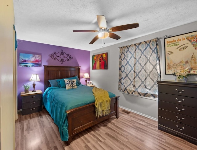 bedroom with light wood-type flooring, ceiling fan, and a textured ceiling