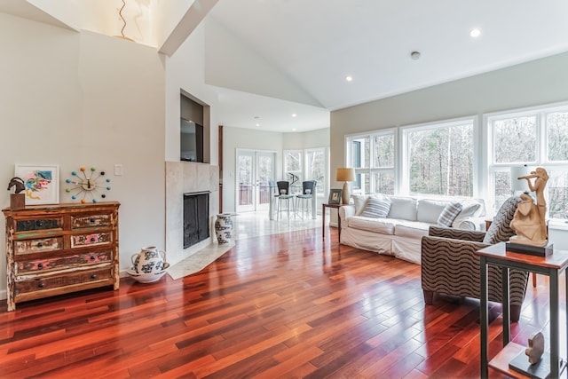 living room with high vaulted ceiling, hardwood / wood-style floors, and a fireplace