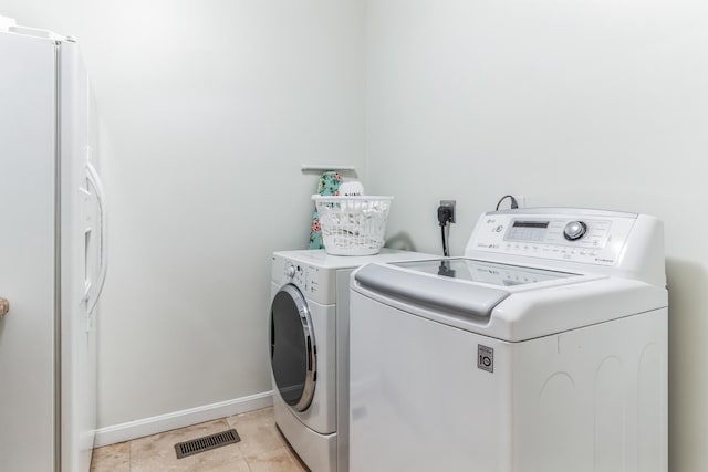 laundry area with light tile patterned flooring and washer and dryer