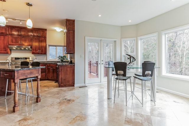 kitchen featuring a wealth of natural light, hanging light fixtures, stove, dark stone countertops, and french doors