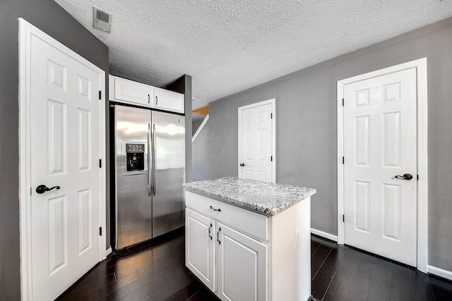 kitchen featuring dark hardwood / wood-style flooring, white cabinetry, stainless steel fridge with ice dispenser, a textured ceiling, and a center island