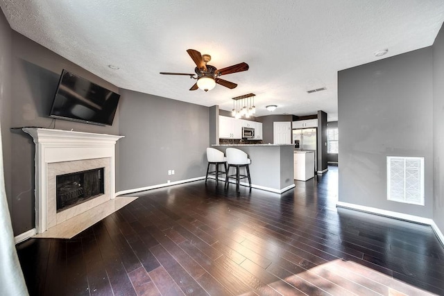 unfurnished living room featuring a textured ceiling, a premium fireplace, ceiling fan, and dark hardwood / wood-style flooring