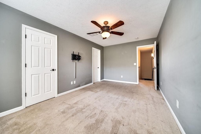 unfurnished bedroom with a textured ceiling, light colored carpet, and ceiling fan