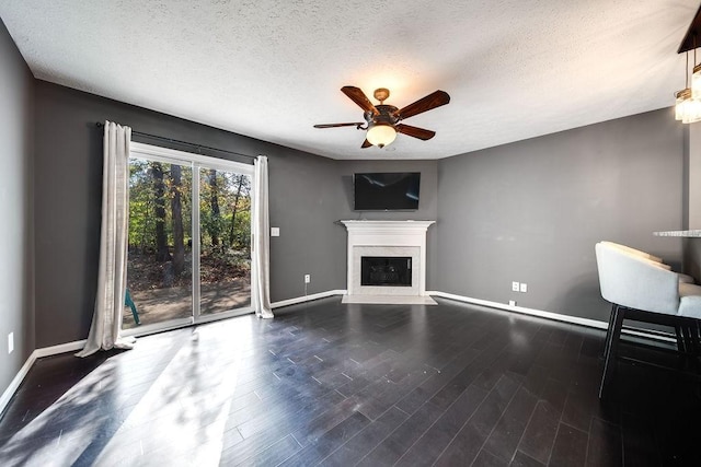 unfurnished living room featuring ceiling fan, dark wood-type flooring, and a textured ceiling