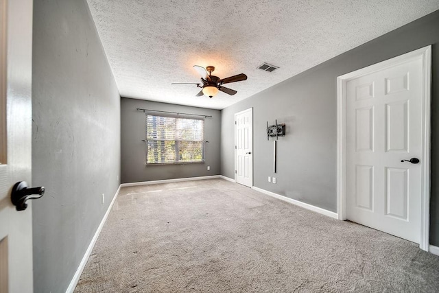 carpeted empty room with ceiling fan and a textured ceiling