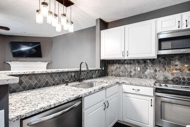 kitchen featuring hanging light fixtures, sink, backsplash, white cabinets, and stainless steel appliances