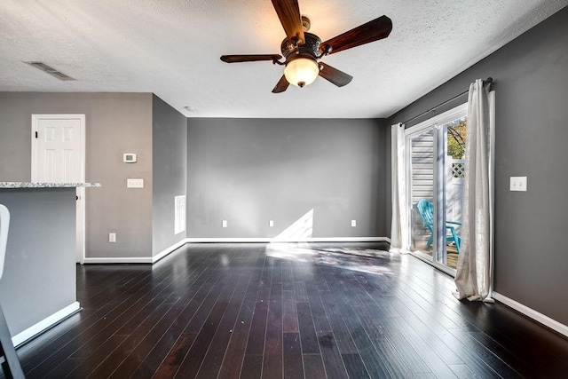 unfurnished living room featuring ceiling fan, dark hardwood / wood-style floors, and a textured ceiling