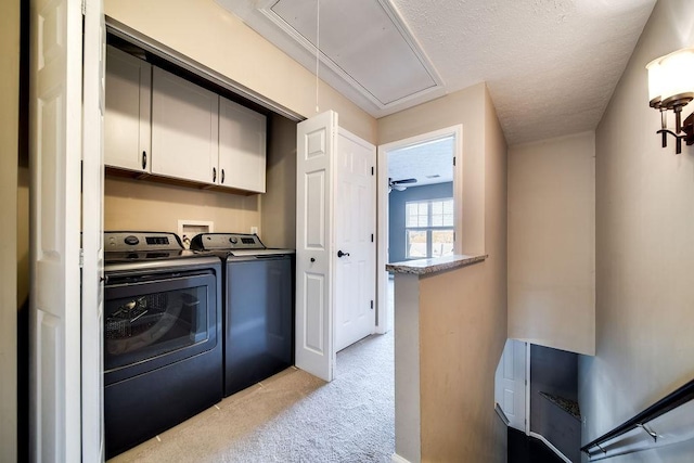 washroom featuring cabinets, light colored carpet, separate washer and dryer, and a textured ceiling