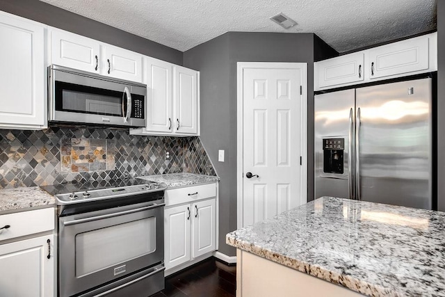 kitchen with white cabinets, tasteful backsplash, and stainless steel appliances