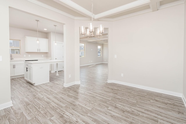 interior space with light hardwood / wood-style flooring, pendant lighting, white cabinetry, a center island, and ornamental molding