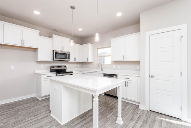 kitchen featuring white cabinets, pendant lighting, appliances with stainless steel finishes, and a kitchen island