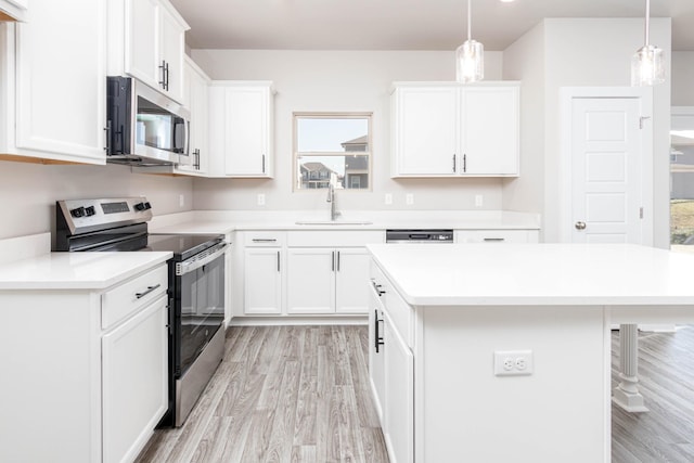 kitchen featuring sink, decorative light fixtures, white cabinetry, and appliances with stainless steel finishes