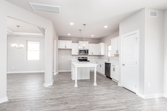 kitchen featuring pendant lighting, a center island, white cabinetry, and stainless steel appliances