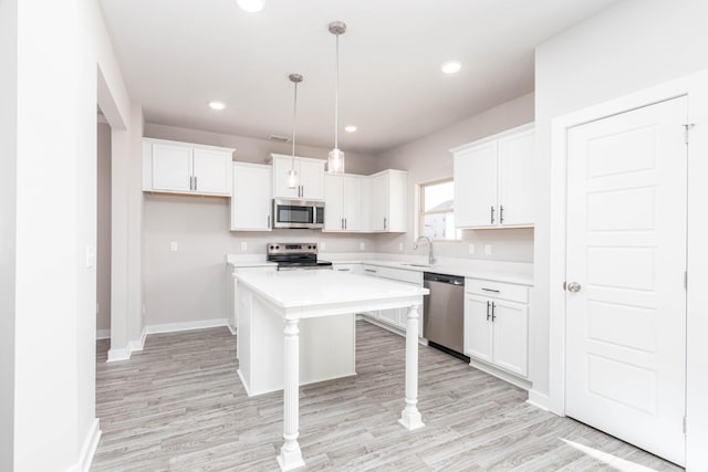 kitchen featuring a center island, appliances with stainless steel finishes, white cabinets, decorative light fixtures, and sink