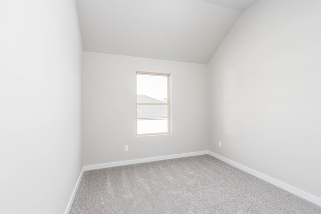 carpeted empty room with vaulted ceiling