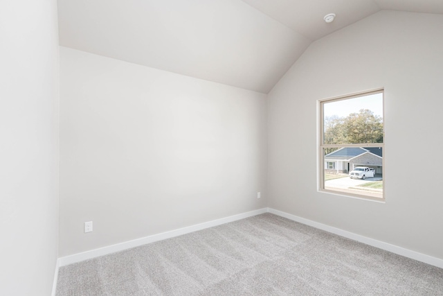 unfurnished room featuring light carpet and vaulted ceiling