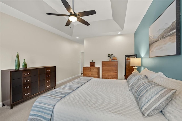 carpeted bedroom with ceiling fan and a tray ceiling