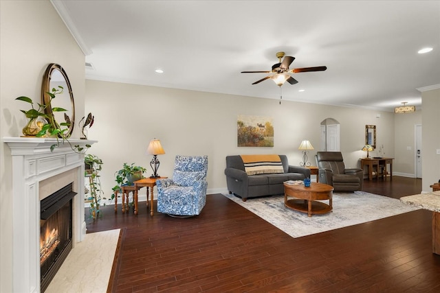 living room featuring ceiling fan, dark hardwood / wood-style floors, a high end fireplace, and crown molding