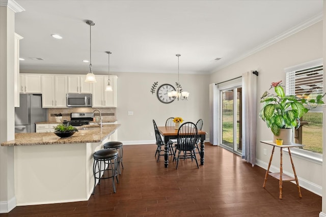 kitchen featuring decorative backsplash, decorative light fixtures, white cabinets, and stainless steel appliances