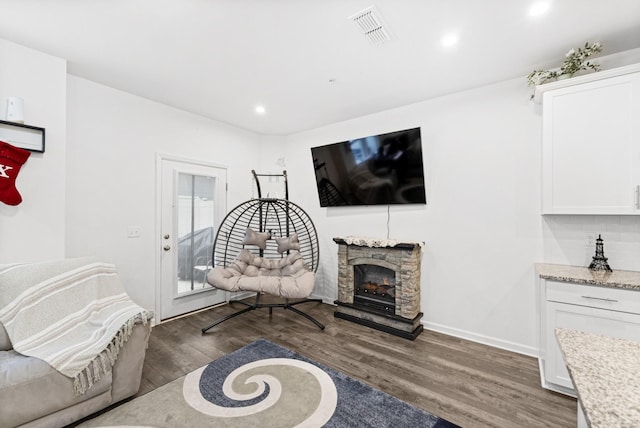 living area with dark hardwood / wood-style flooring and a stone fireplace