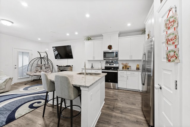 kitchen featuring sink, dark wood-type flooring, appliances with stainless steel finishes, light stone counters, and white cabinets