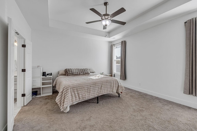 bedroom with ceiling fan, a raised ceiling, and light carpet