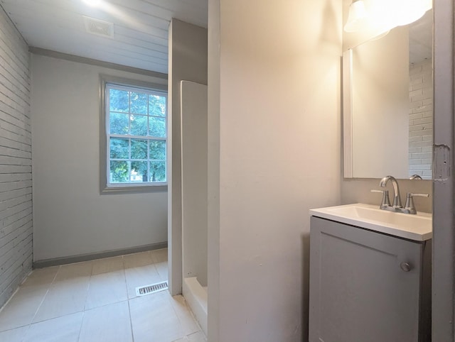 bathroom with tile patterned floors, brick wall, and vanity