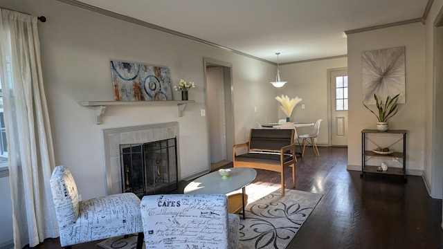 living room with dark hardwood / wood-style flooring, ornamental molding, and a tiled fireplace