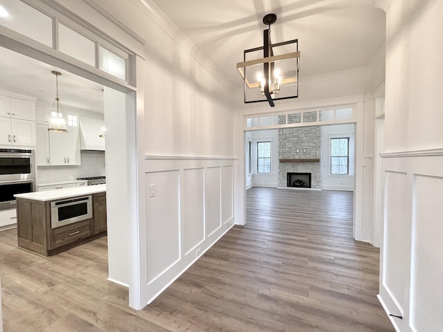 kitchen featuring white cabinets, decorative light fixtures, an inviting chandelier, ornamental molding, and stainless steel appliances